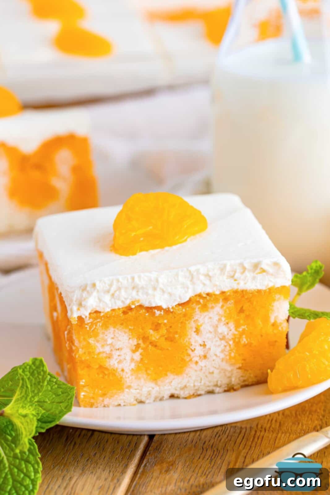 A plate with a serving of Orange Creamsicle Poke Cake. 