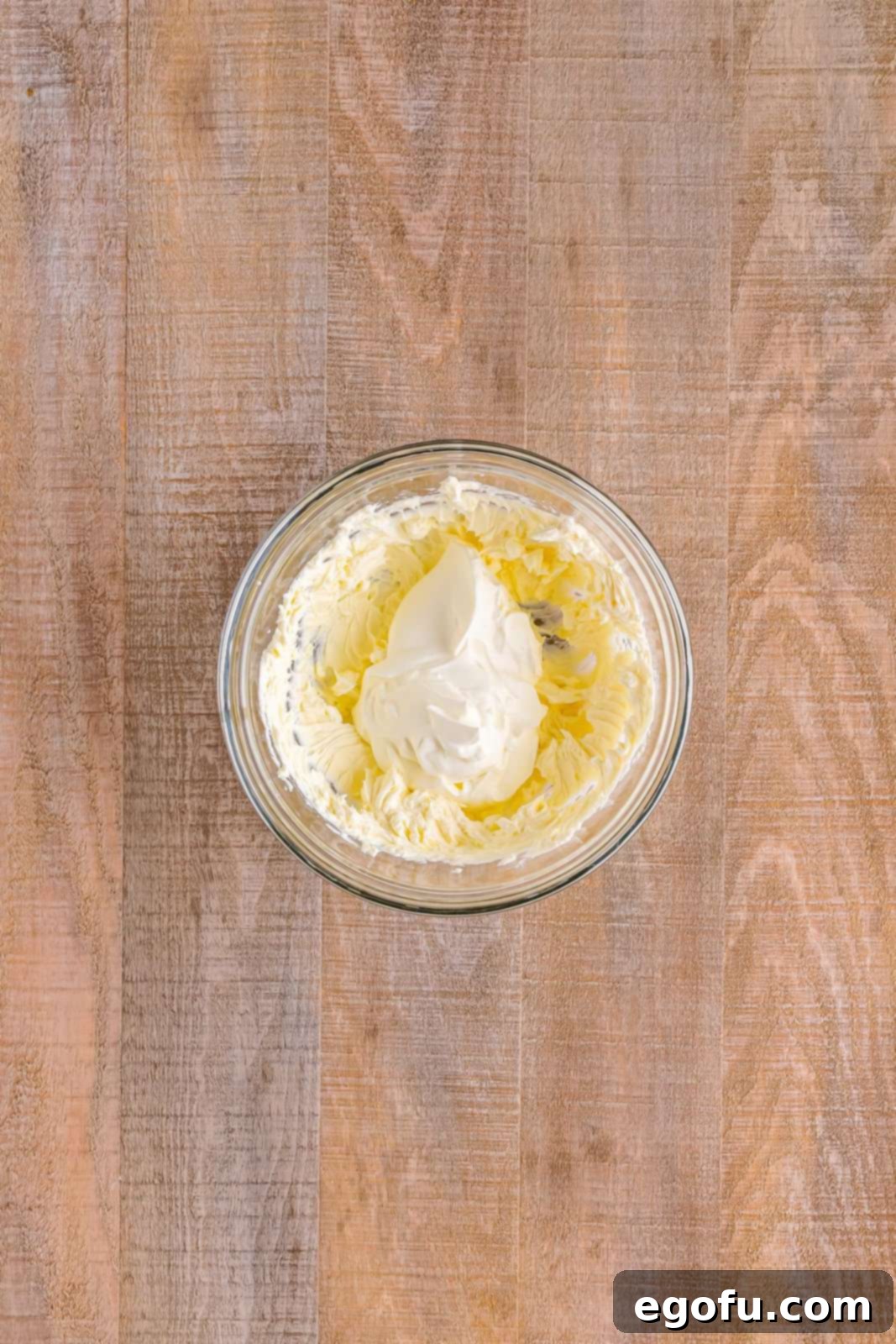 A mixing bowl containing softened cream cheese and sour cream, ready to be blended into a smooth base.