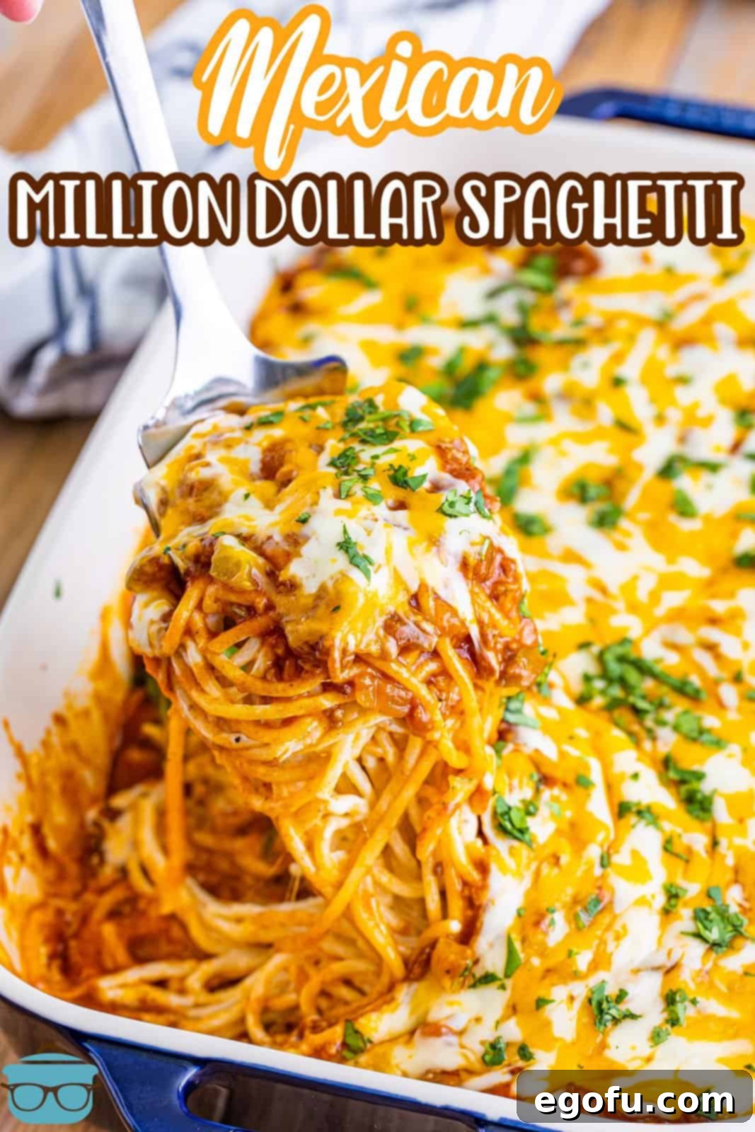 Serving utensil holding a serving of Mexican million dollar spaghetti over a baking dish.