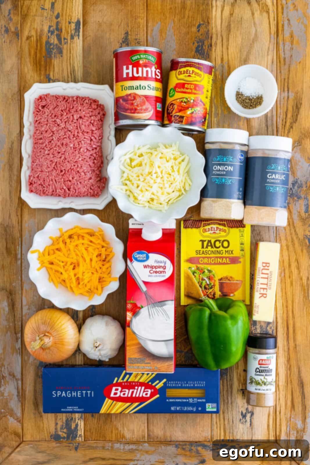 Ground beef, onion, bell pepper, taco seasoning, garlic powder, onion powder, ground cumin, salt, black pepper, tomato sauce, enchilada sauce, butter, garlic cloves, heavy cream, shredded monterey jack and cheddar cheese, spaghetti, and cilantro.