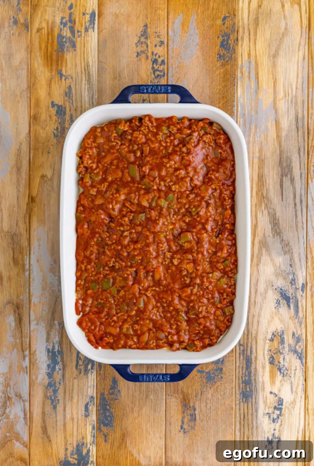 Meat sauce on top of pasta in a baking dish.