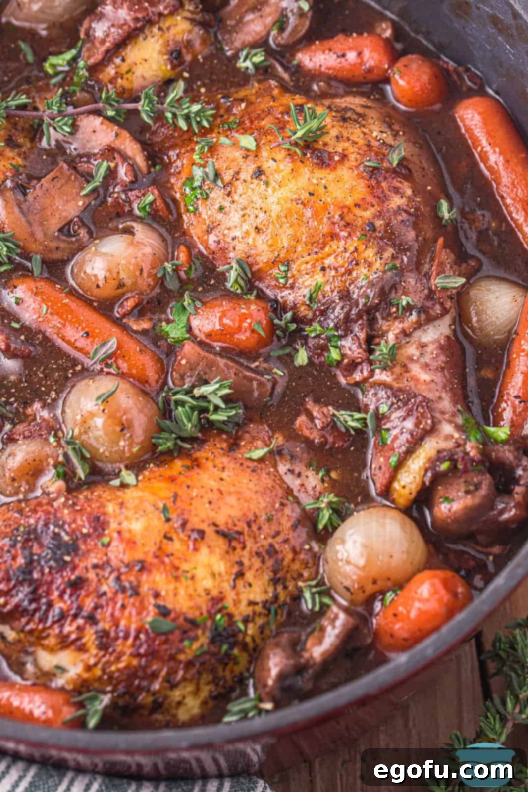 A perfectly cooked pot of Coq Au Vin, showcasing tender chicken, vegetables, and a rich, dark red wine sauce.