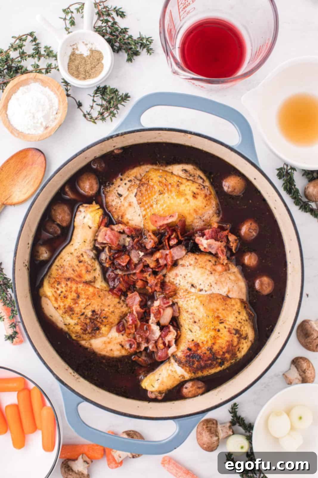 All the Coq Au Vin ingredients, including seared chicken and crispy bacon, simmering together in the pot.