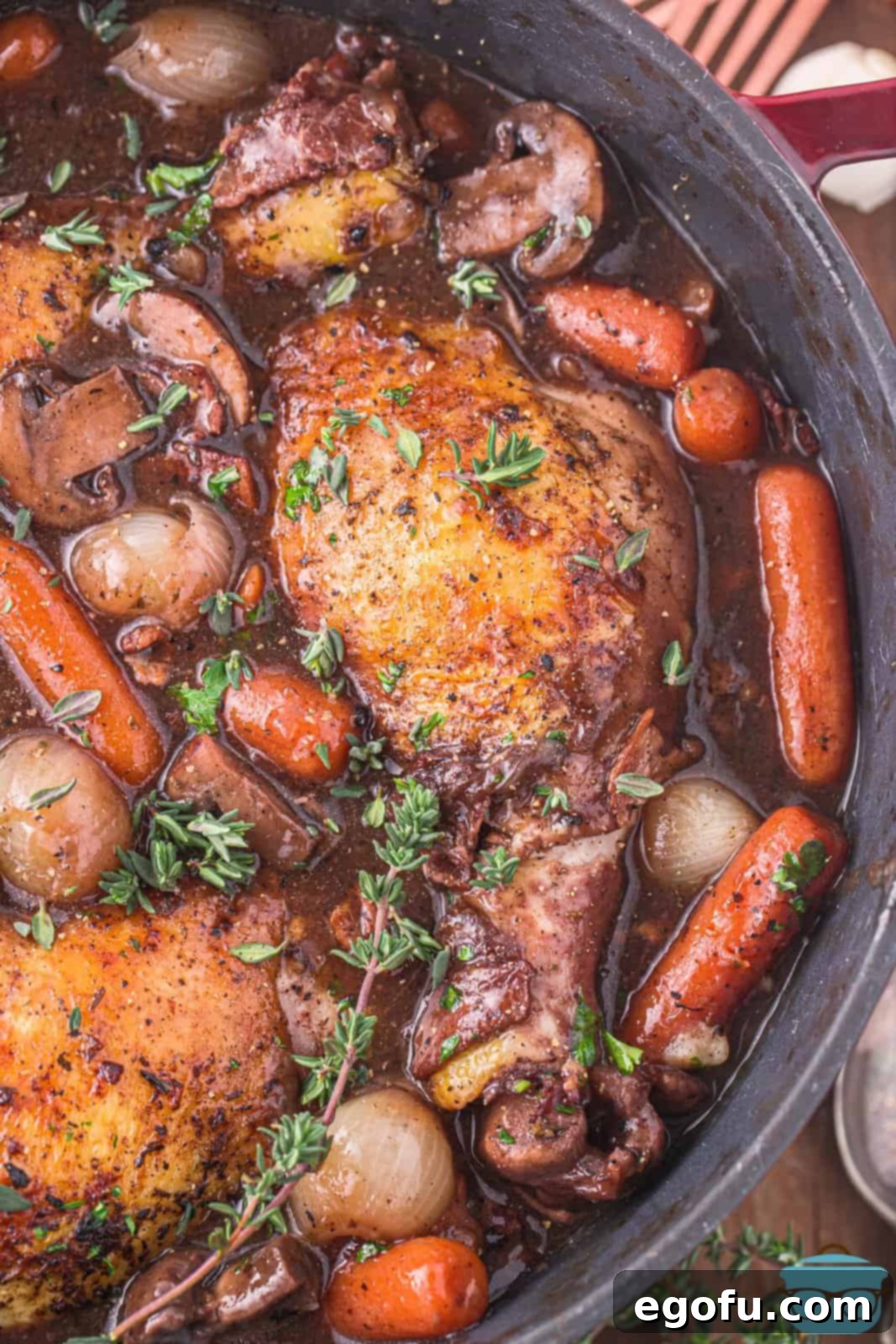 A close-up of the finished Coq Au Vin in the pot, showcasing the rich sauce, tender chicken, and vibrant vegetables.