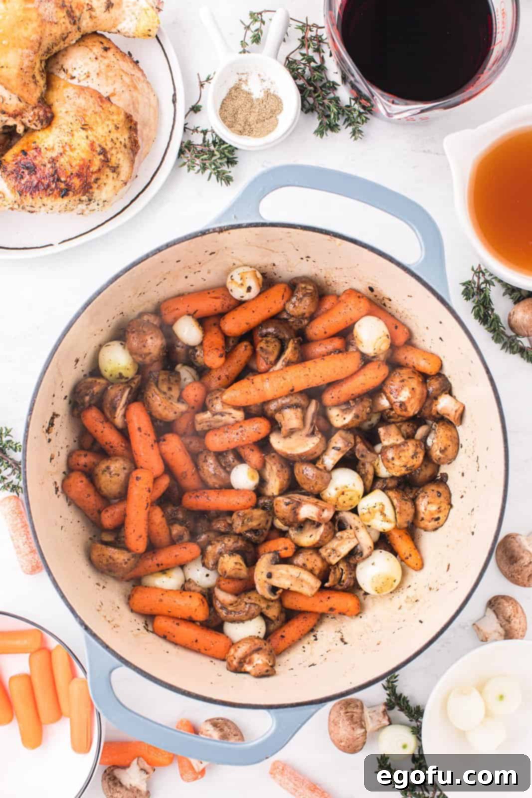 Sautéed mushrooms, carrots, and pearl onions, seasoned with garlic and thyme, simmering in the pot.