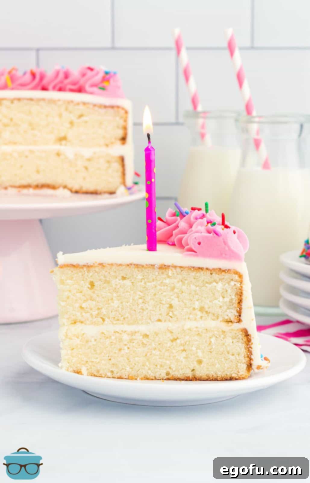 A slice of homemade white cake that is layered and has a homemade frosting and candles on top.
