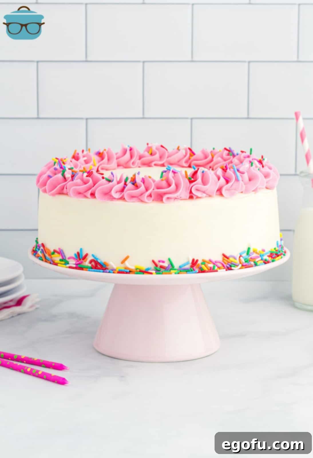 A homemade white cake on a cake pedistal.