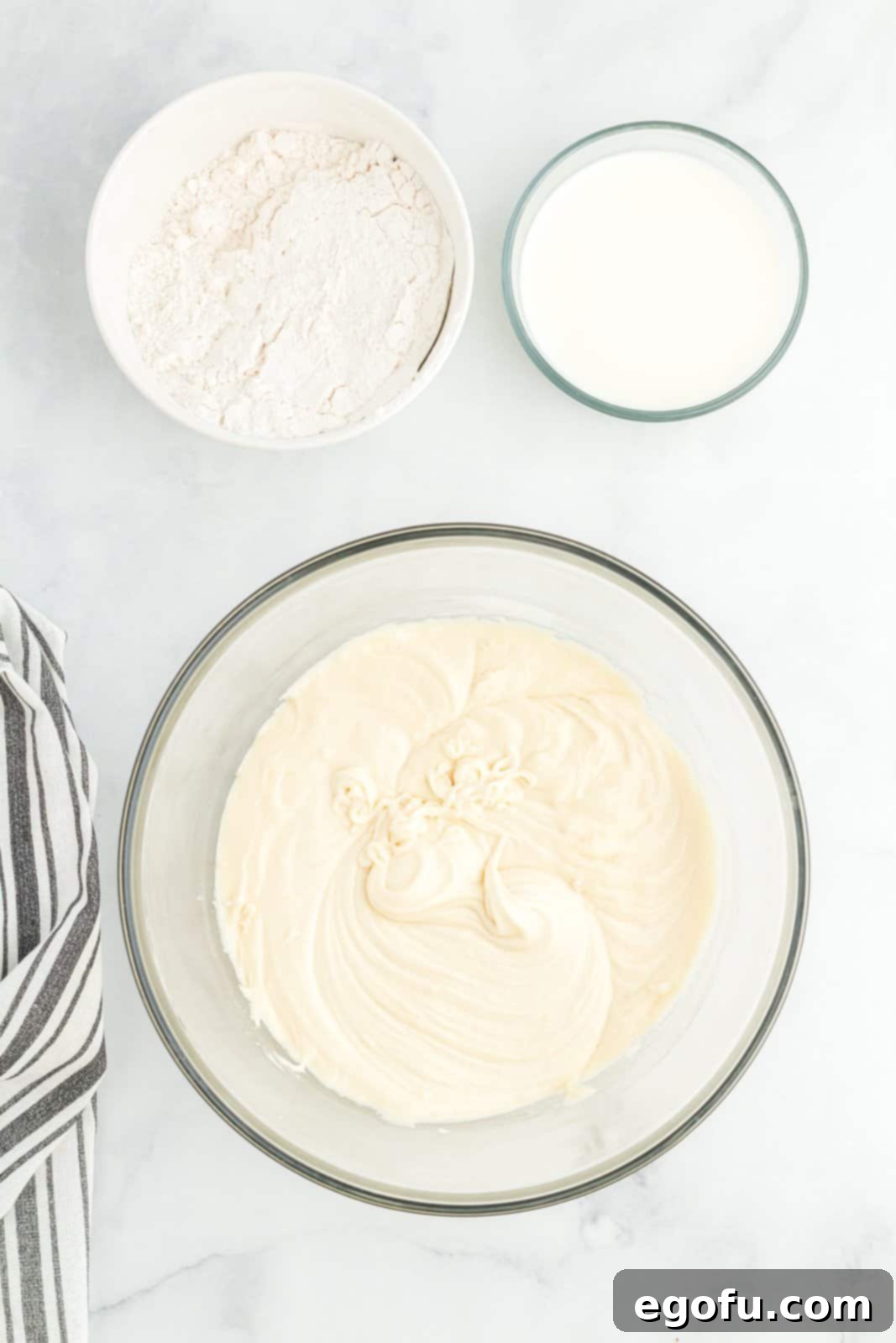 A bowl with cake batter and two other smaller bowls with dry ingredients.