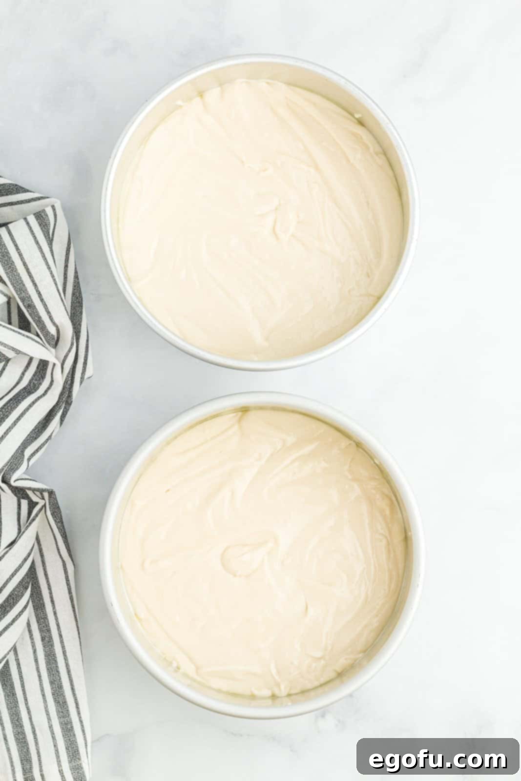 Two cake pans with homemade white cake batter in them.