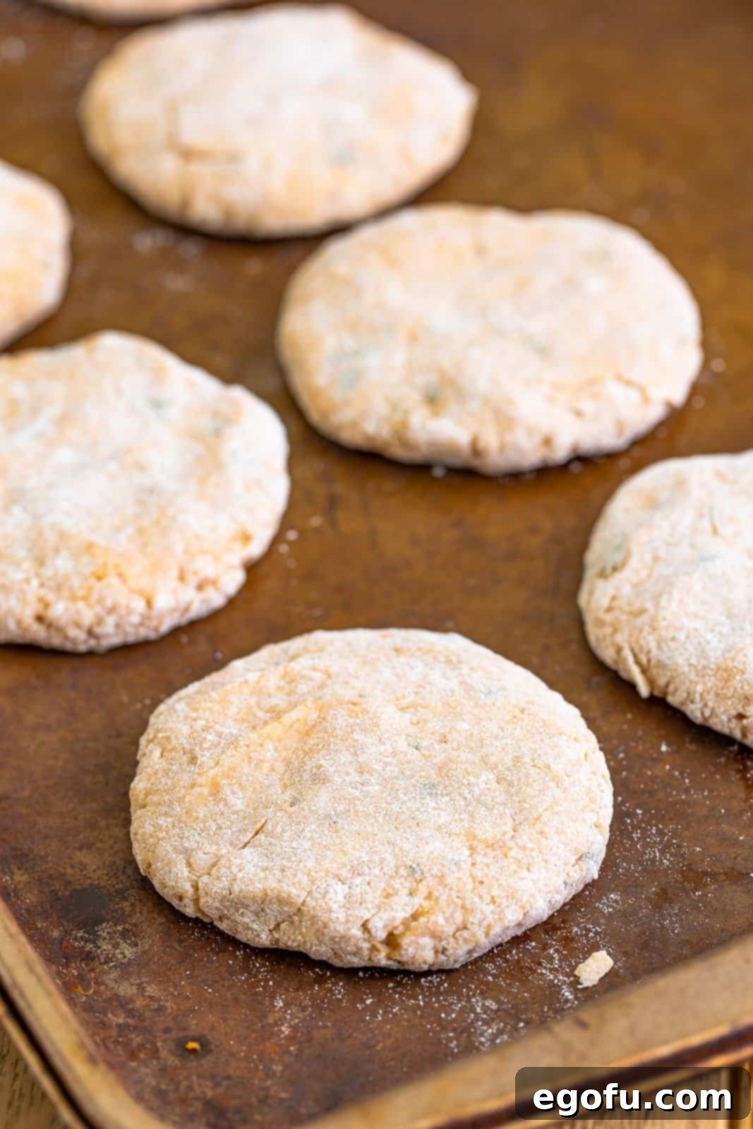 Flour coated chicken patties on a baking sheet.