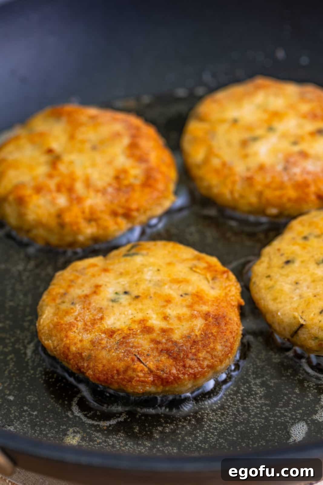 Chicken Patties in oil in a hot pan.