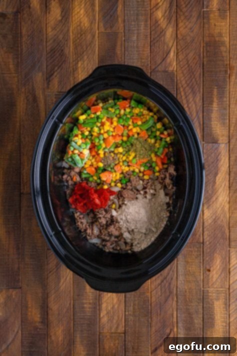 Comforting Slow Cooker Shepherd's Pie 13 Slow Cooker with beef, frozen vegetables, tomato paste, water, gravy mix, and herbs and spices.