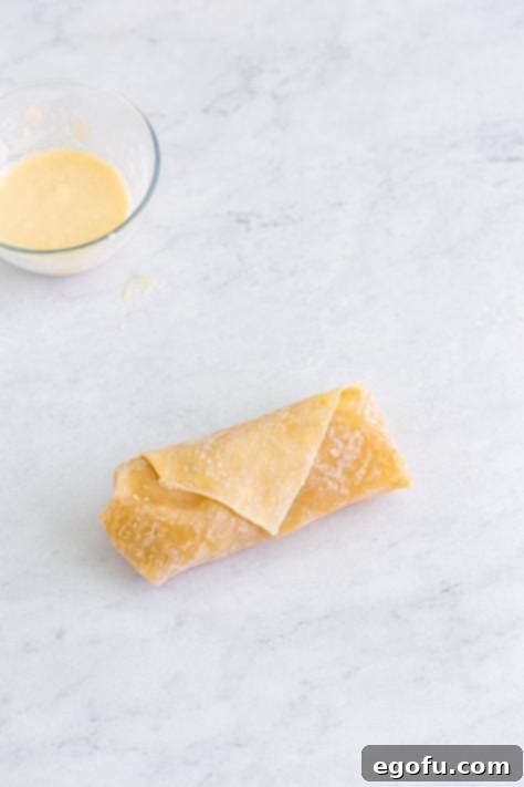 A rolled up egg roll with apple pie filling.