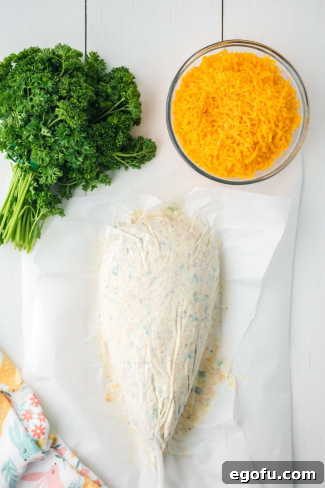 Bunny's Garden Cheeseball 7 A newly shaped carrot cheeseball, still nestled on parchment paper, ready to be coated with more cheddar cheese and transferred to its serving platter.