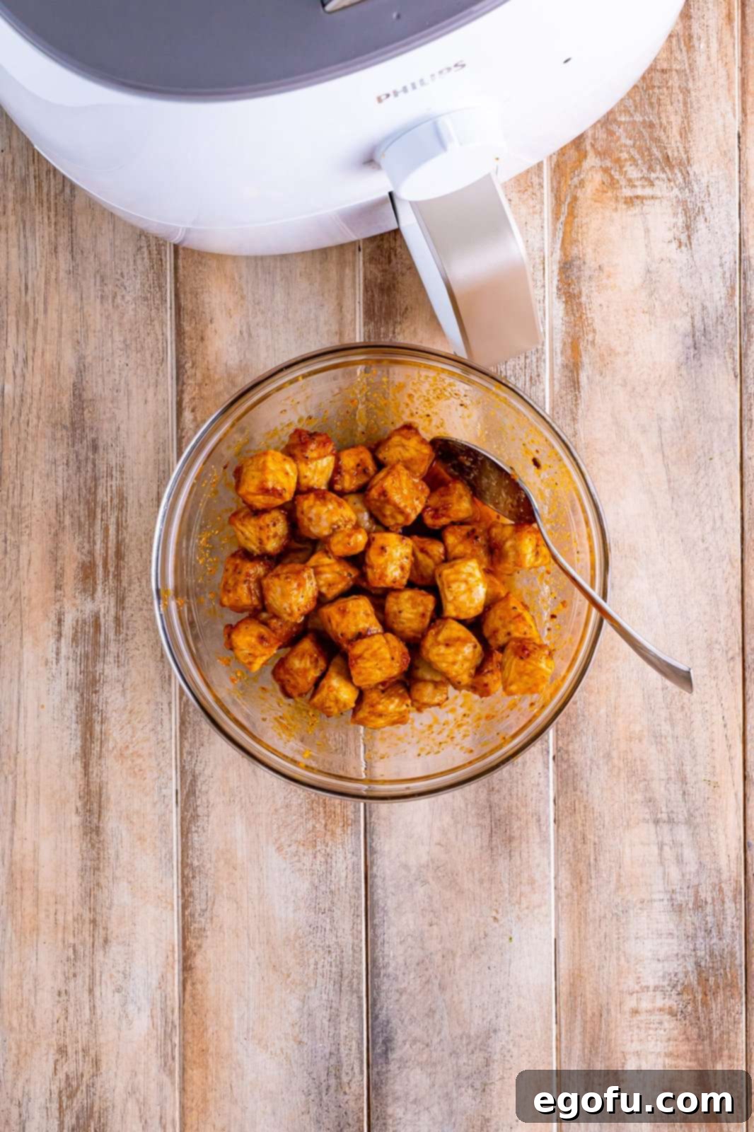Crispy Air Fried Pork Bites 8 Air Fryer Pork bites being tossed in melted butter.