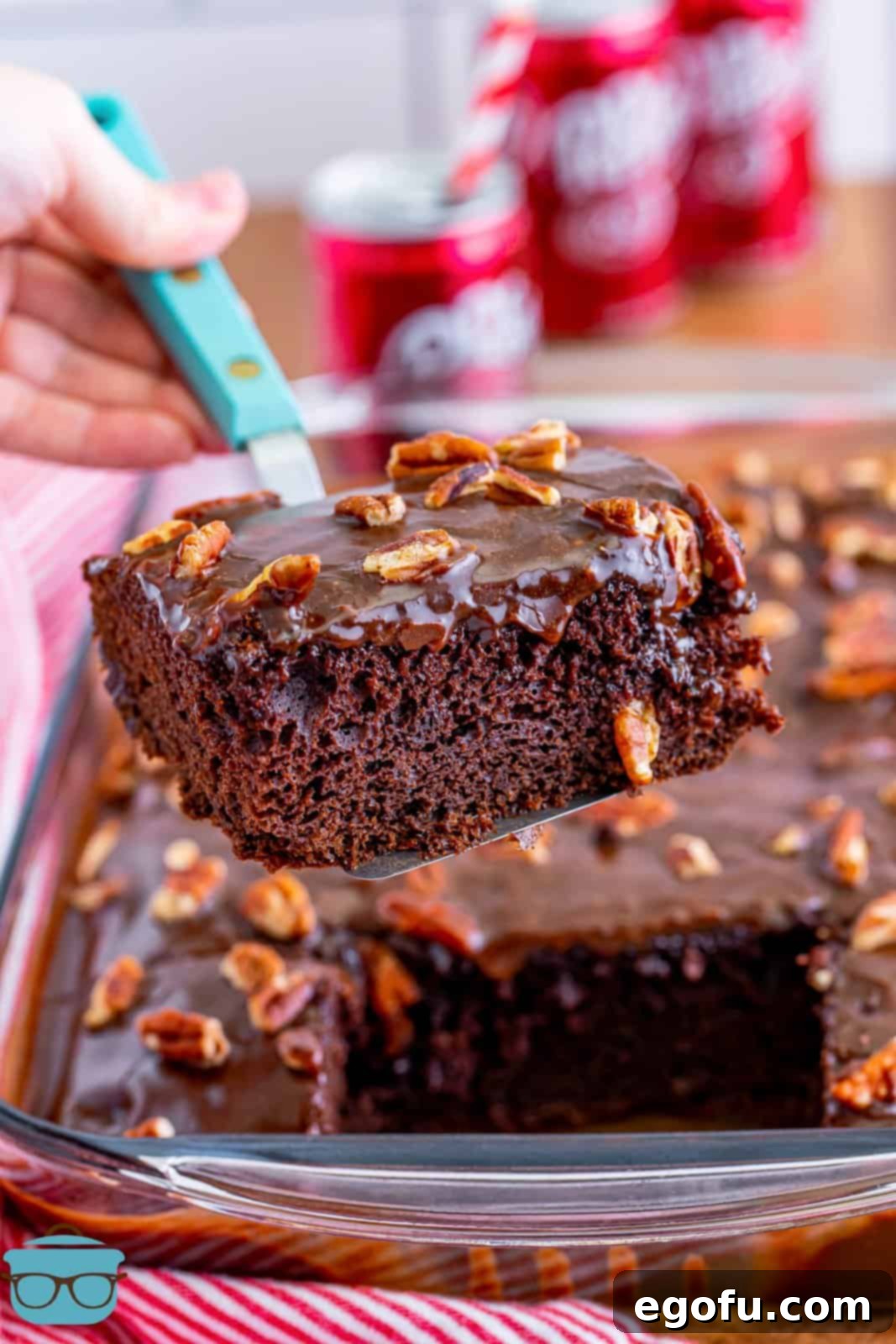 A utensil holding a slice of Dr Pepper Cake, showcasing its moist texture and rich frosting.