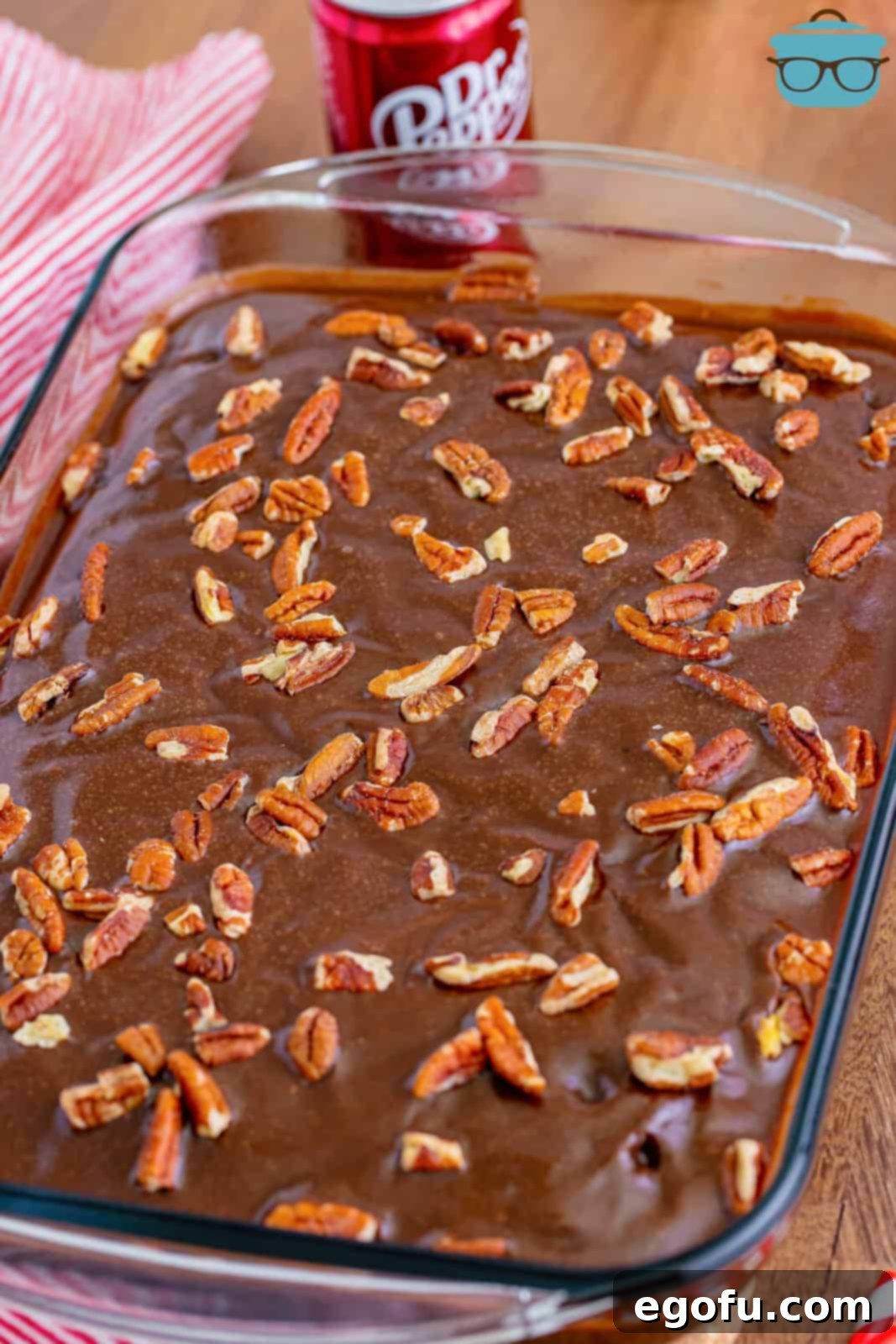A fully frosted Dr Pepper Cake, adorned with chopped nuts, ready for slicing.