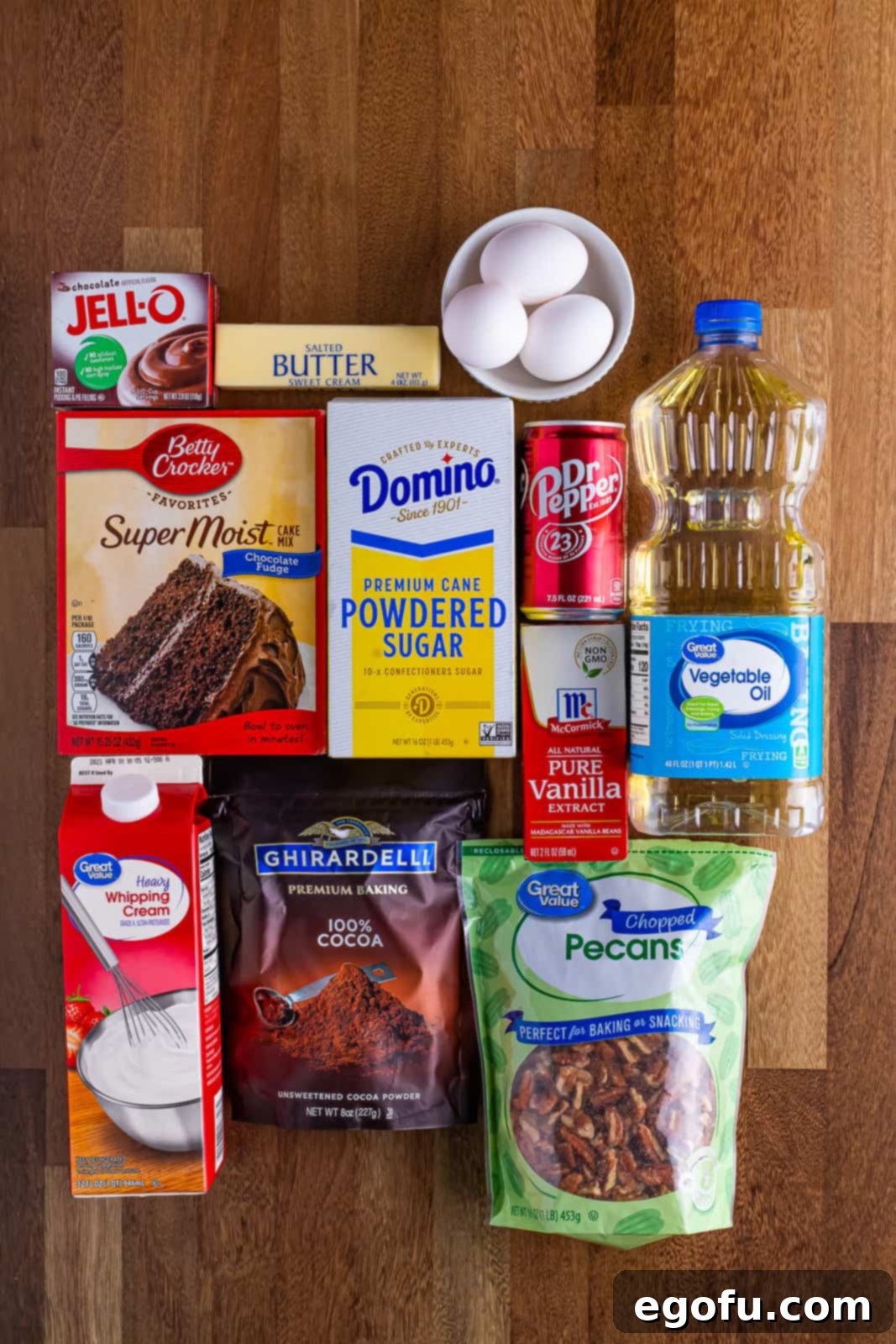 All the ingredients neatly laid out: chocolate fudge cake mix, instant chocolate pudding, eggs, oil, Dr Pepper, salted butter, cocoa powder, heavy cream, powdered sugar, vanilla extract, and chopped pecans.