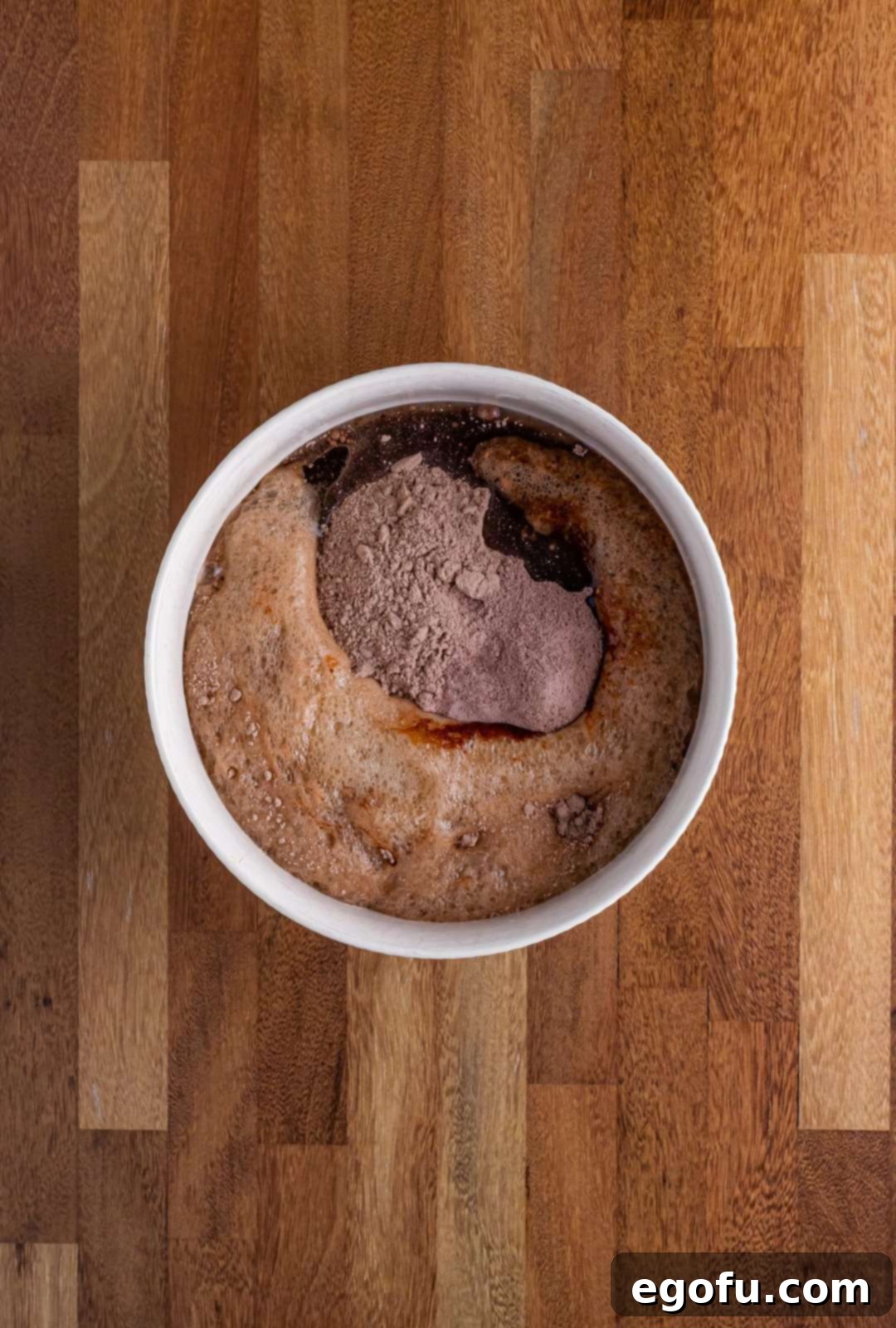 A mixing bowl with cake mix, dry pudding mix, eggs, oil, and Dr. Pepper being combined with an electric mixer.