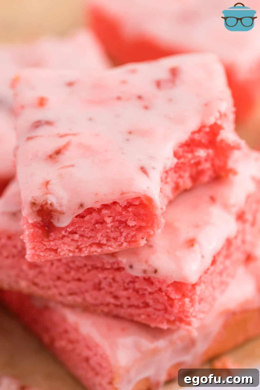 Strawberry Swirl Brownie Bliss 2 A stack of four moist and chewy Strawberry Brownies, with one having a bite taken out, revealing its soft, pink interior.