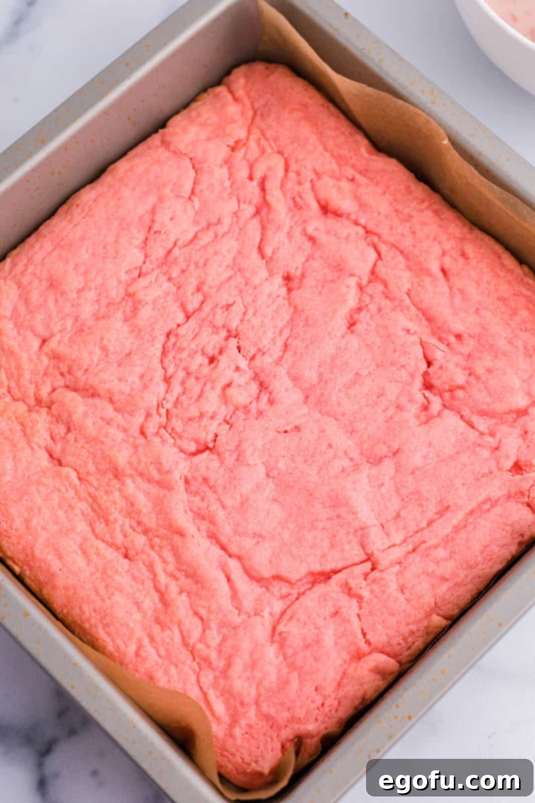 Strawberry Swirl Brownie Bliss 7 Freshly baked strawberry brownies in a pan, cooling on a wire rack, with their edges slightly crispy and centers soft.