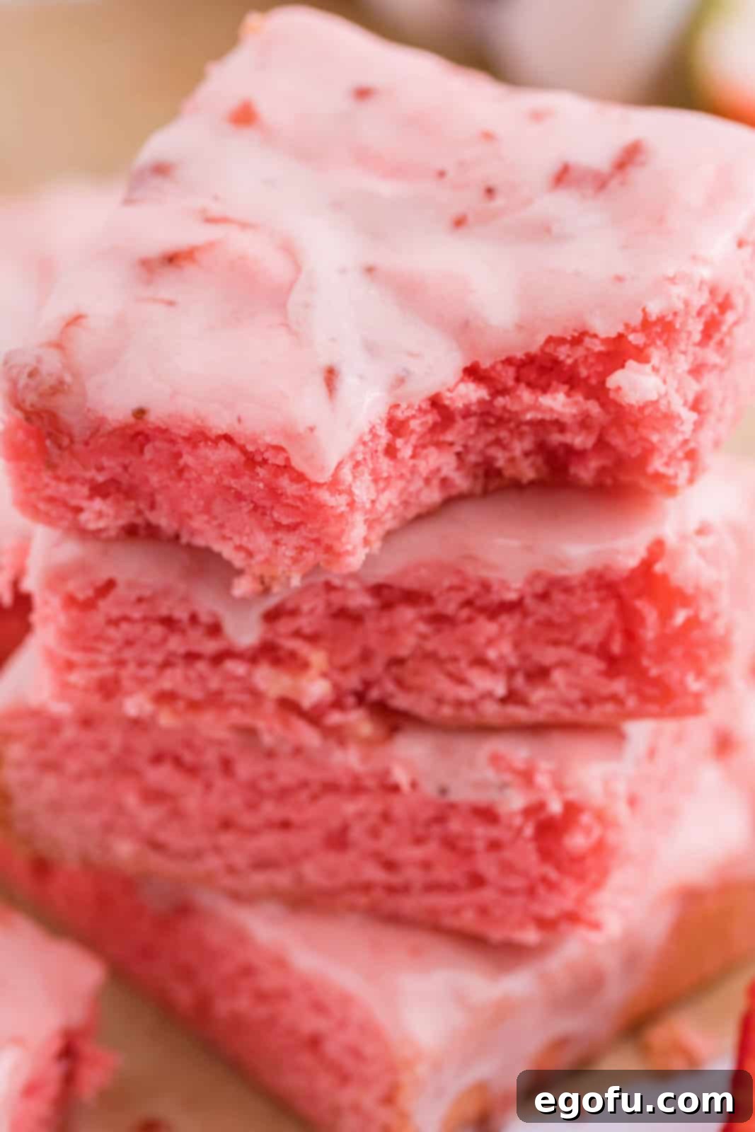 Strawberry Swirl Brownie Bliss 9 A perfectly arranged stack of three Strawberry Brownies, with the top brownie having a delicious bite taken out, highlighting its rich texture and inviting appearance.