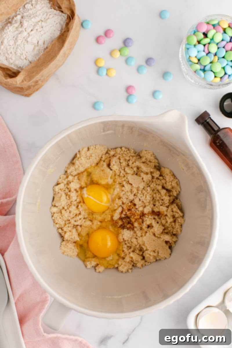 A mixing bowl with vanilla, eggs, butter, light brown sugar and granulated sugar.