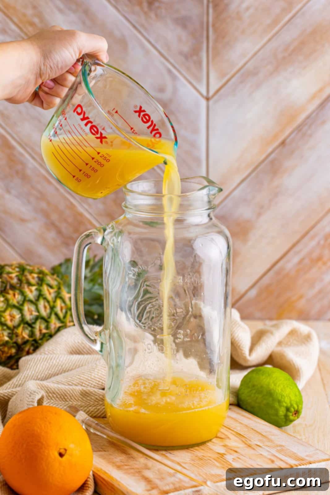 Island Dream Sip 4 A pitcher with pineapple and orange juice being combined for Rum Punch.