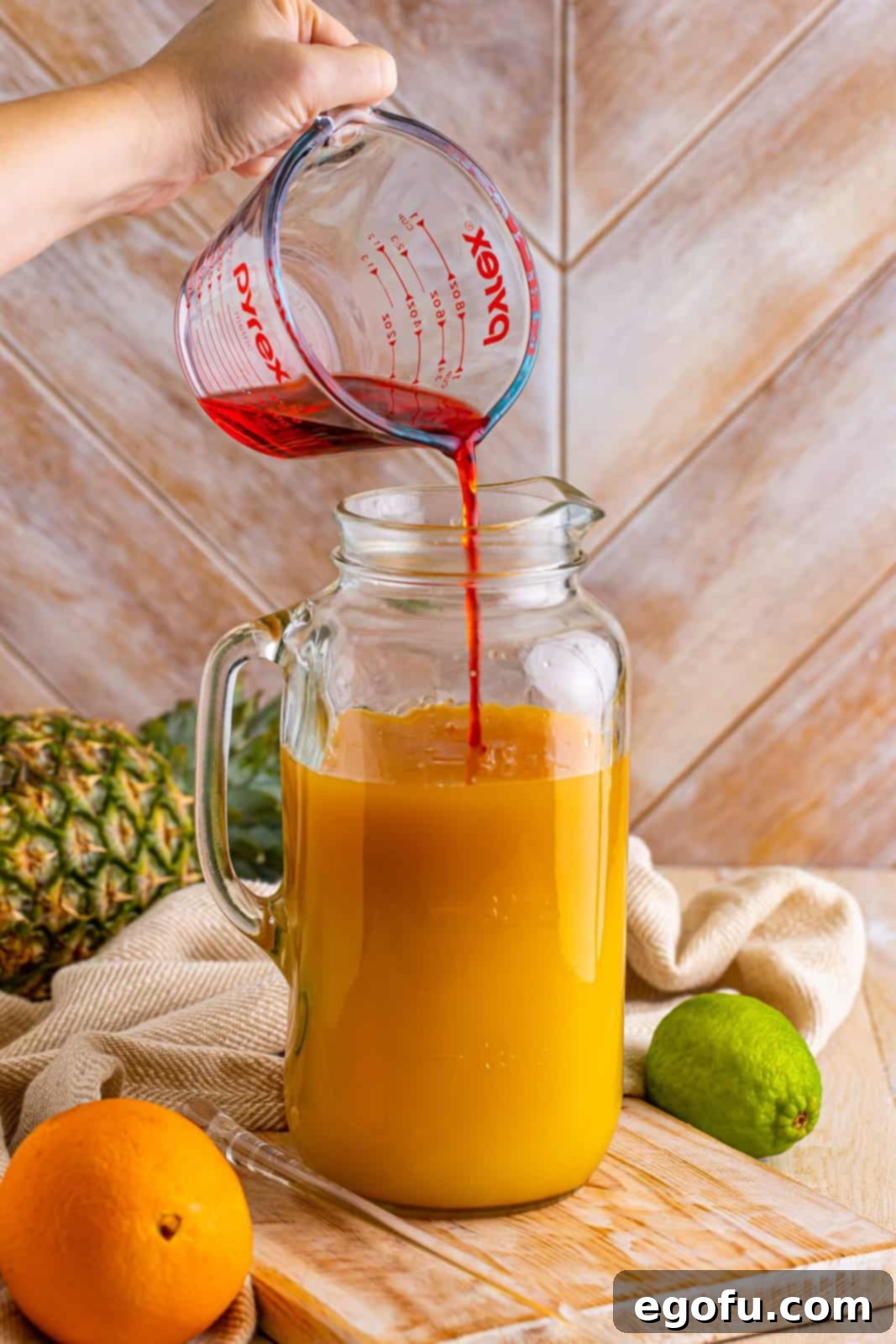 Island Dream Sip 7 A pitcher with pineapple, orange juice, dark rum, grenadine, and white rum, the final mix before stirring.