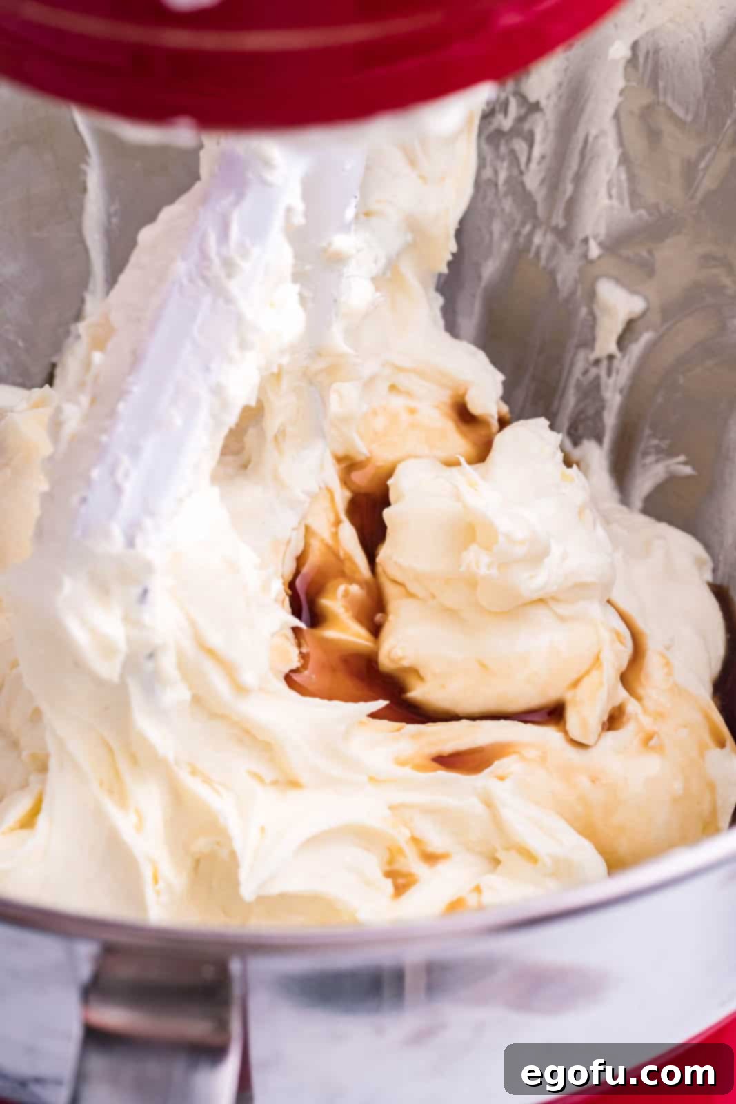 Vanilla extract being added to a cream cheese, heavy cream, flour, and sugar mixture. 