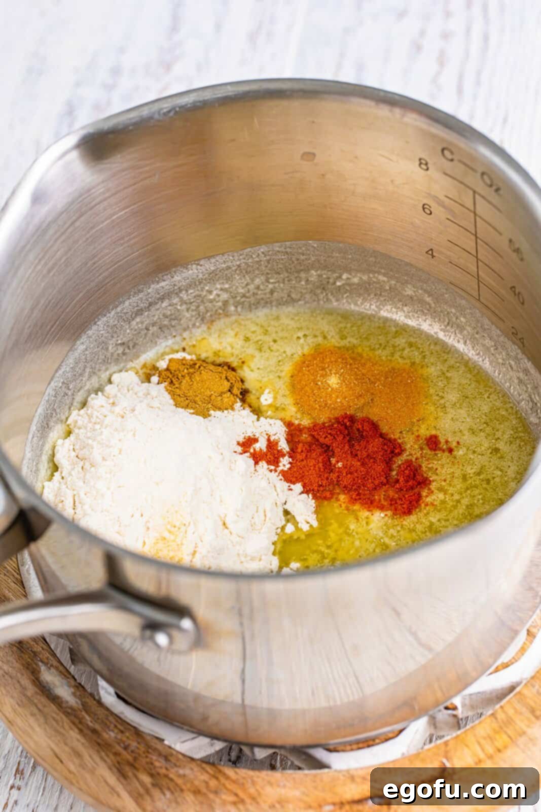 A saucepot showing melted butter combined with flour, garlic powder, onion powder, cumin, and paprika, forming a flavorful roux.