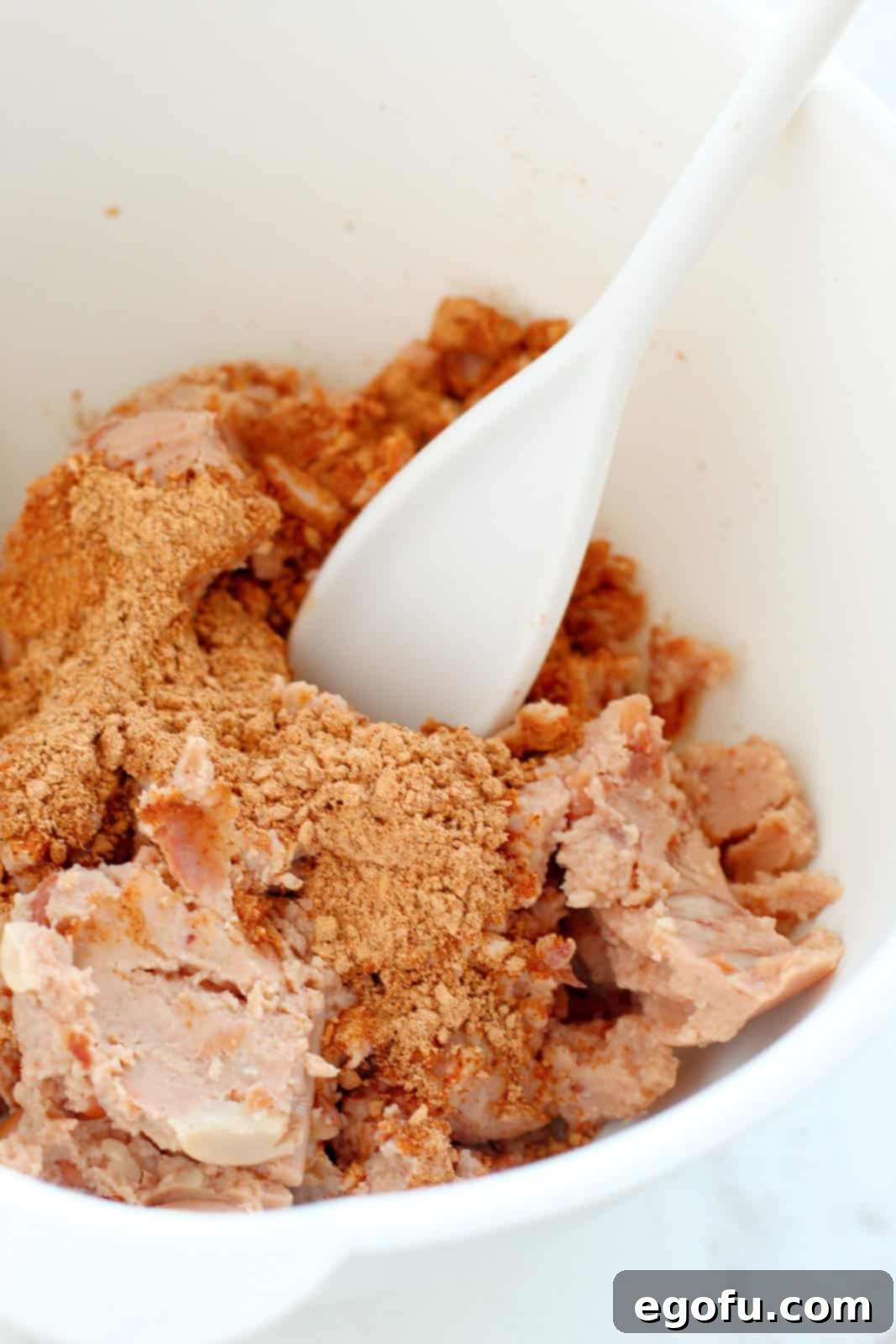 Refried beans and taco seasoning in a mixing bowl.