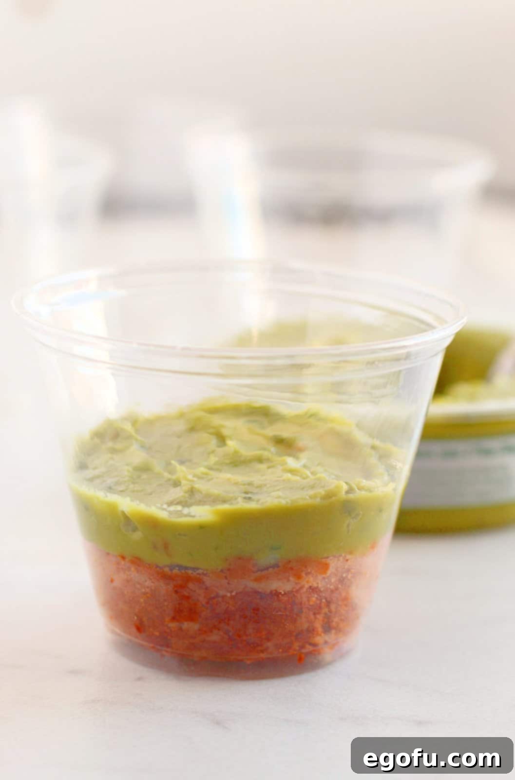A cup with refried beans and guacamole.