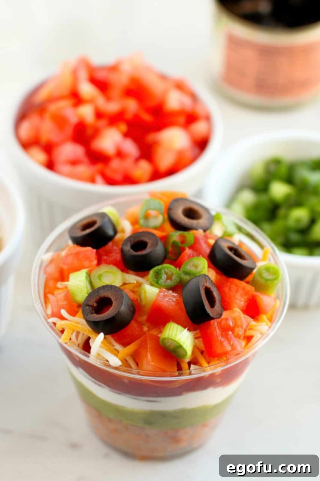 Looking down on the top few layers of the 7 layer dip in a cup.