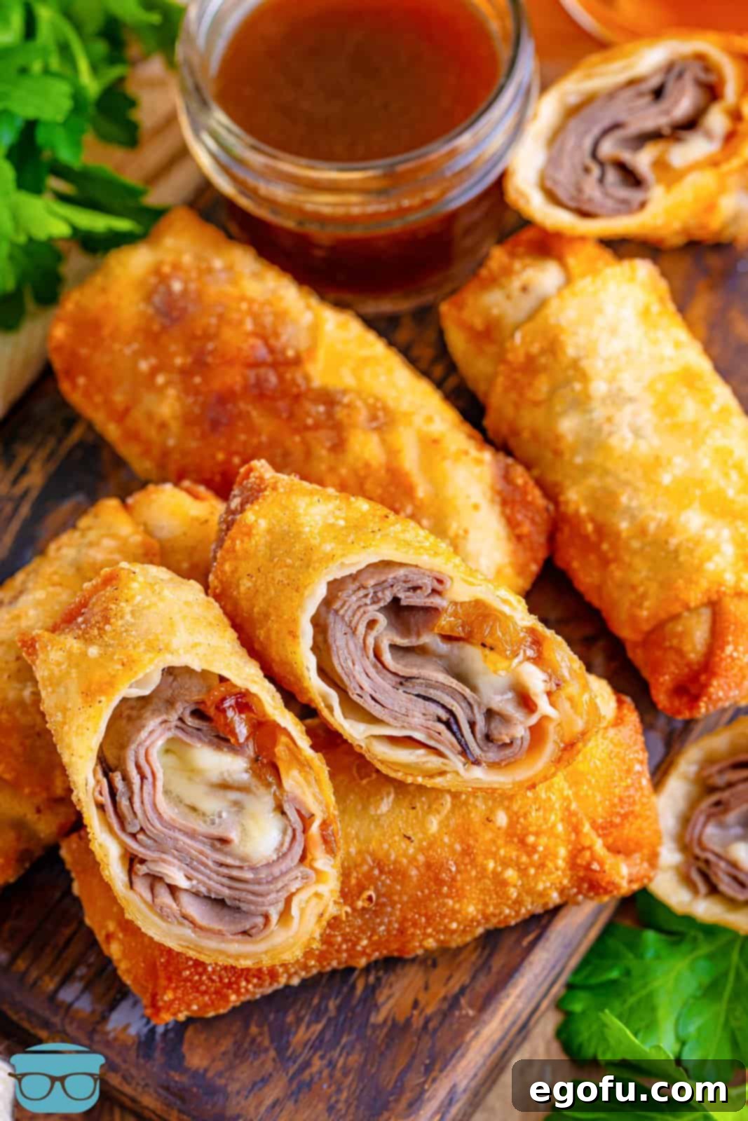 A broken open French Dip Egg Roll, revealing its savory roast beef and melted cheese filling.