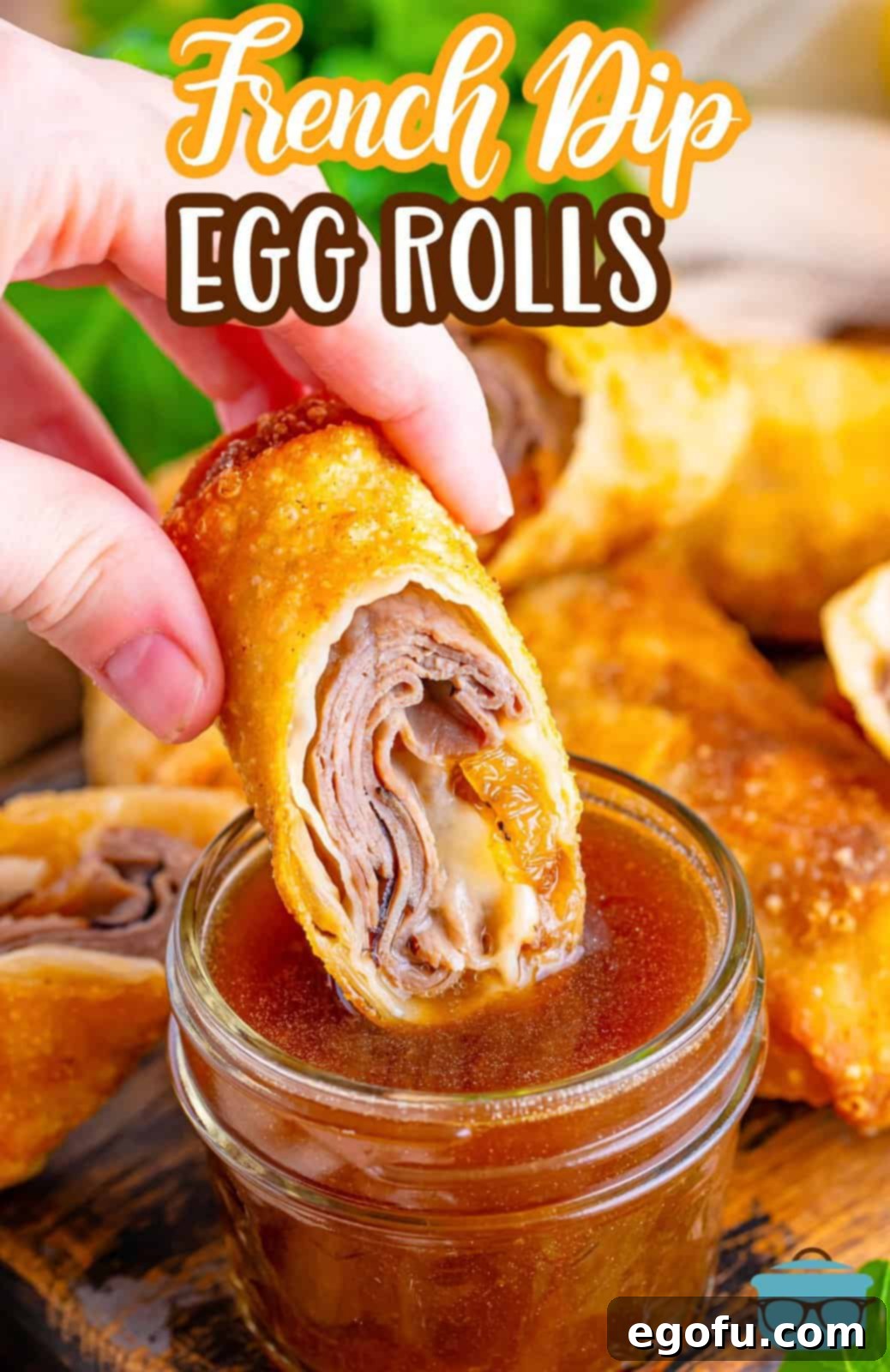A hand holding a French Dip egg roll and dipping it into a small bowl of au jus gravy.