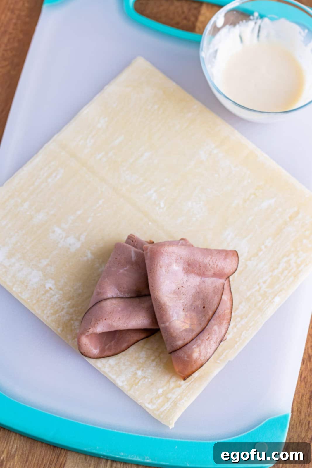 An egg roll wrapper laid out in a diamond shape with two slices of roast beef placed on the bottom corner.