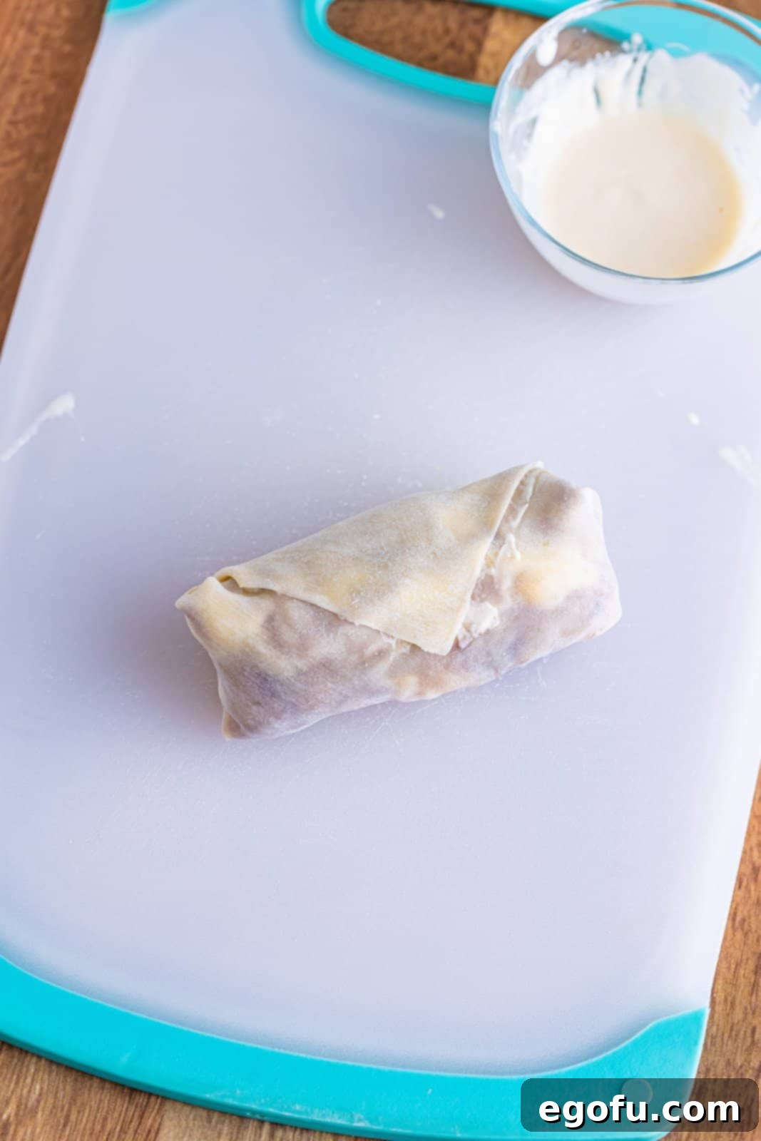 A neatly rolled, uncooked French Dip Egg Roll, ready for frying.