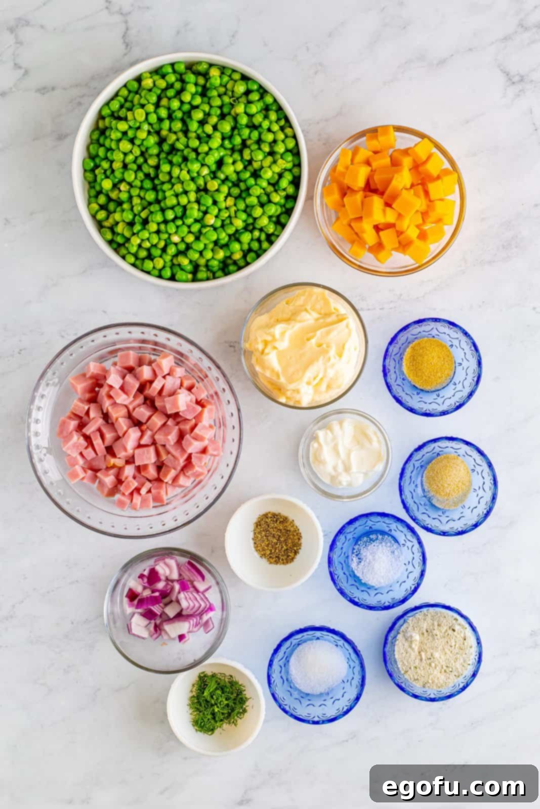 Creamy Garden Pea Salad 4 Mayo, sour cream, ranch seasoning, dill, granulated sugar, garlic powder, onion powder, kosher salt, black pepper, peas, ham, cheddar cheese, and red onion.