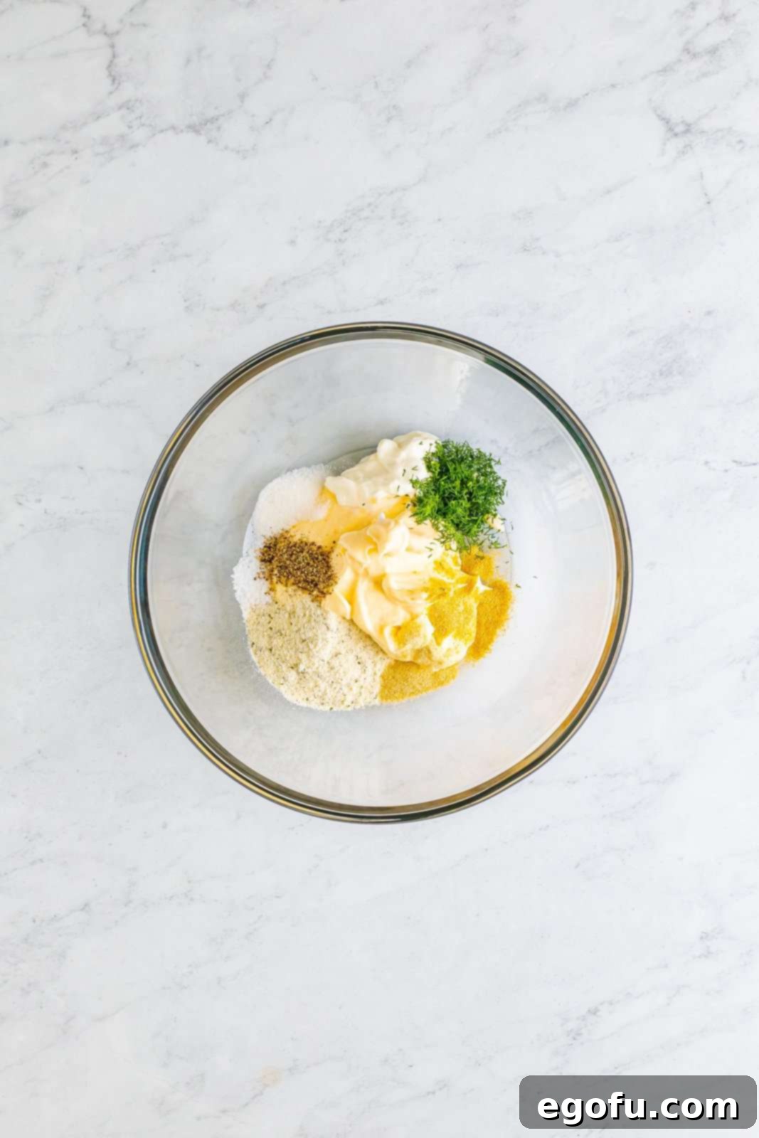 Creamy Garden Pea Salad 5 A mixing bowl with mayonnaise, sour cream, dried ranch seasoning, fresh dill, sugar, garlic powder, onion powder, kosher salt, and black pepper.