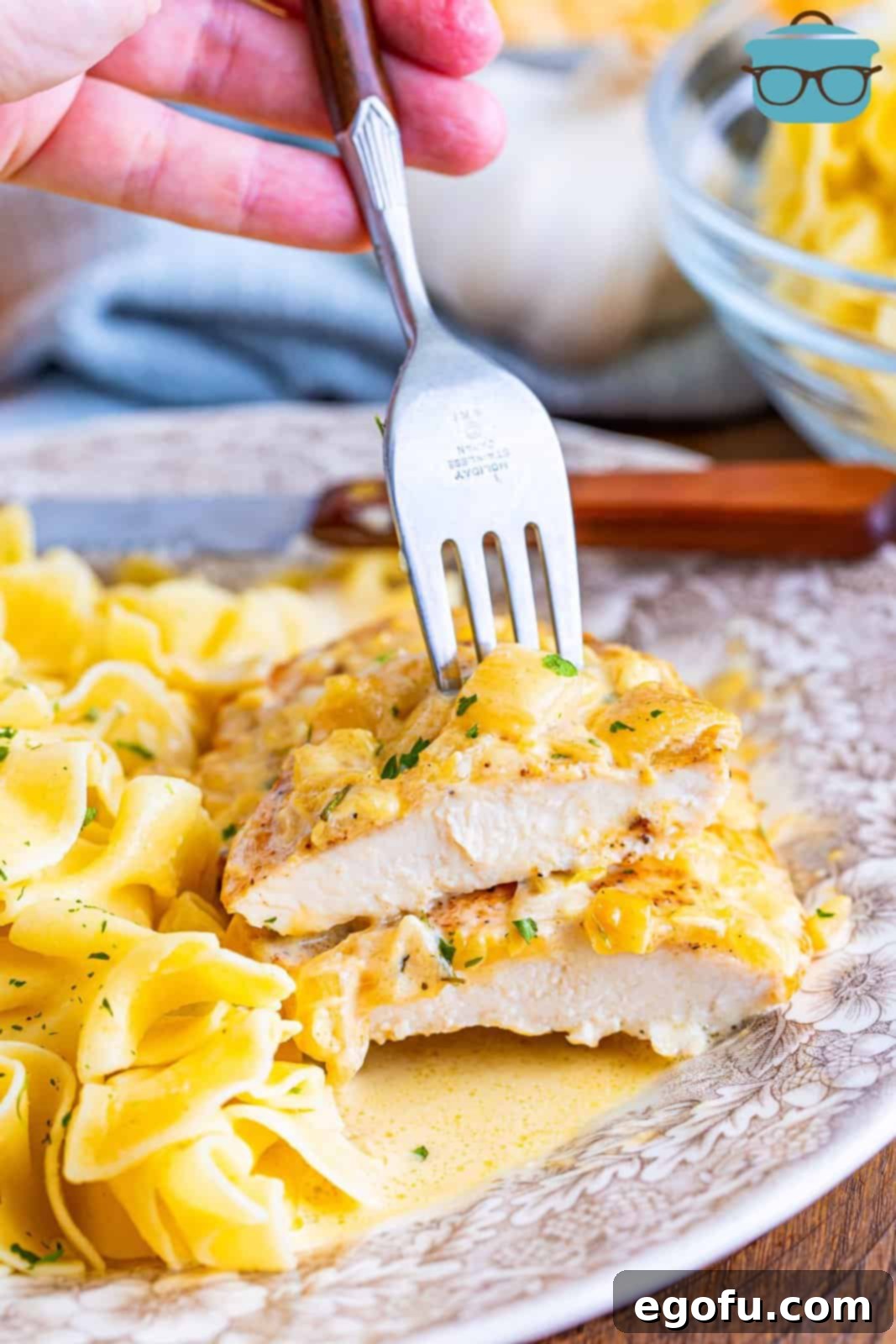 A fork holding a sliced piece of Creamy Garlic Chicken with pasta.