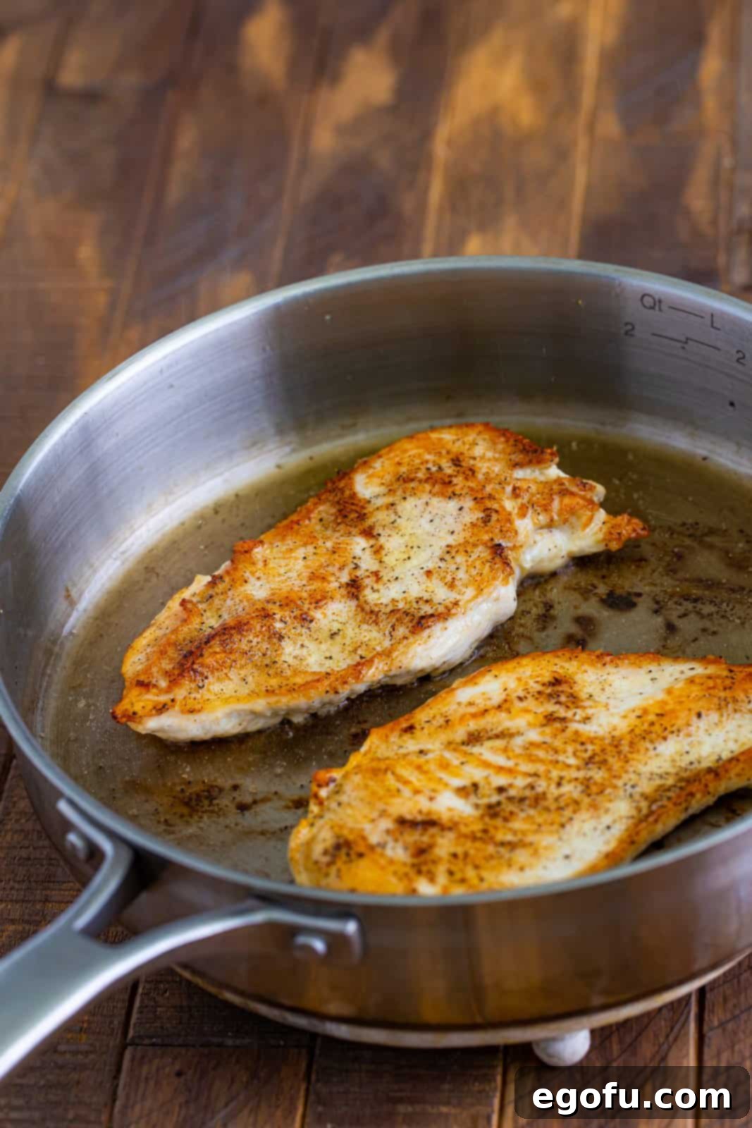 Butterflied chicken breasts in a saucepan with oil.