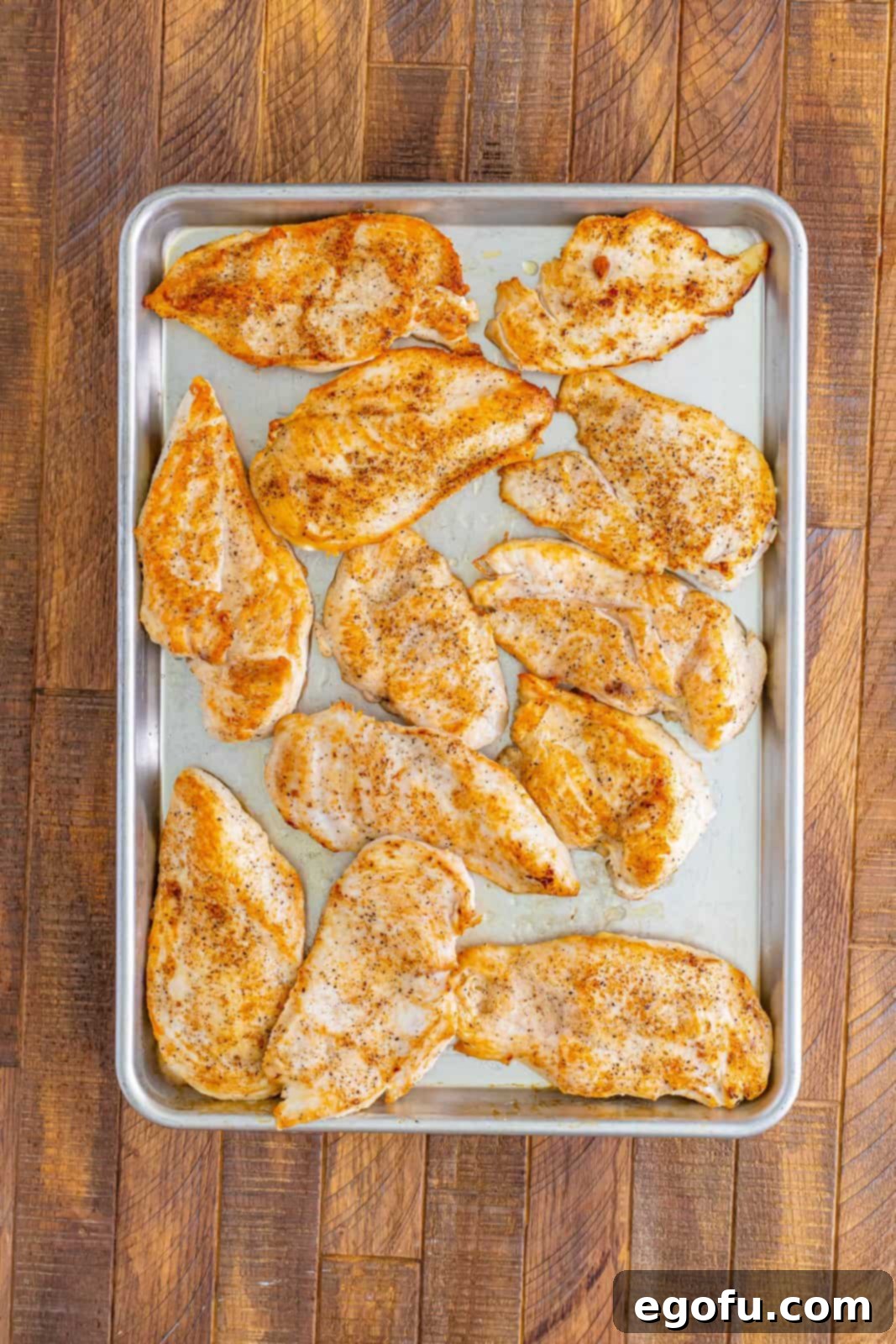 Chicken breasts on a rimmed sheet pan.