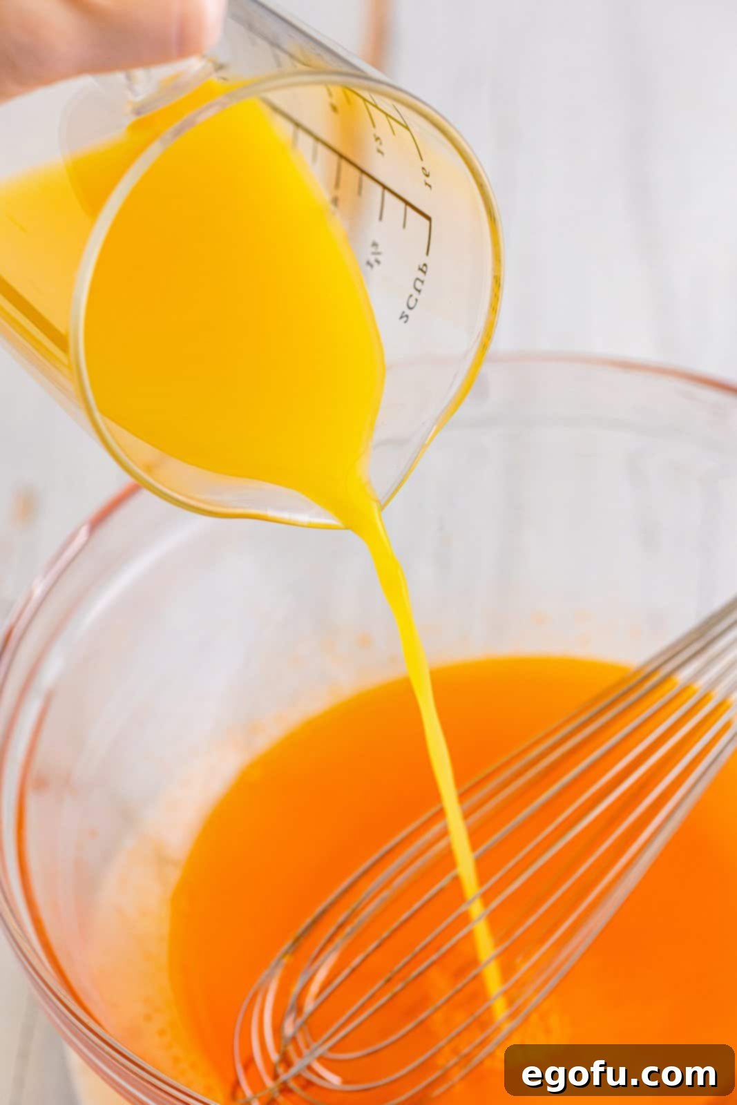 Agave Aurora Shots 7 Orange juice being poured in a mixing bowl with orange jello mix, tequila and water.