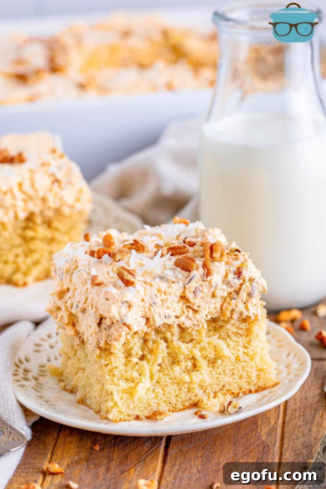 A slice of Butter Pecan Poke cake on a plate with another piece behind it.