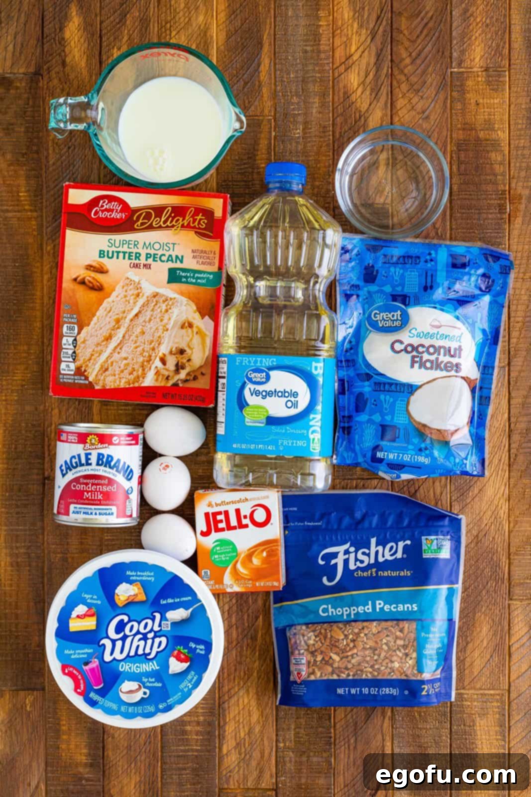 Butter pecan cake mix, eggs, oil, water, whipped topping, sweetened condensed milk, instant butterscotch pudding mix, whole milk, sweetened shredded coconut flakes, and chopped pecans.