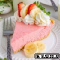 closeup of a slice of strawberry banana jell-o pie on a small round white plate.