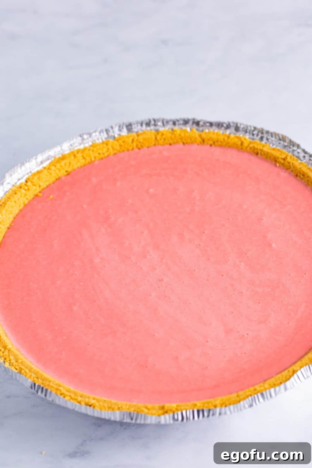 A graham cracker crumb crust and strawberry banana jello pie filling.