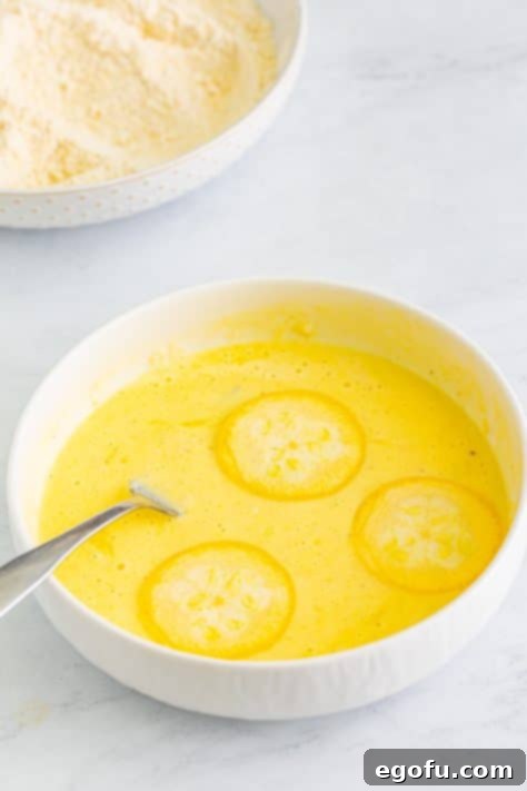 Down Home Fried Squash 14 Three slices of squash being dipped into an egg and buttermilk mixture.