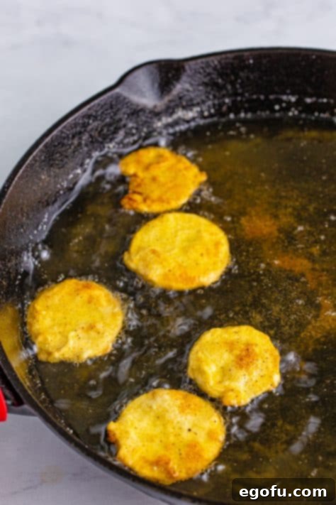 Down Home Fried Squash 16 A skillet with oil frying a few pieces of squash.